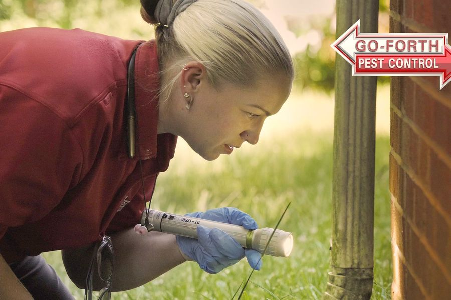 A Go-Forth technician inspecting the foundation of a home with a flashlight